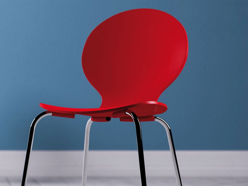 TANTZKY roter moderne Stuhl vor blauer Wand auf grauem Boden,  freier Platz, wir wachsen weiter,