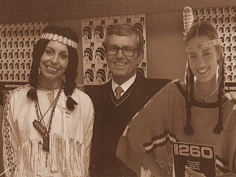 Franz Werner Tantzky hat links Nashuatec Pappaufsteller Indianerin und Helga Tantzky, verkleidet als Indianerin,im Arm