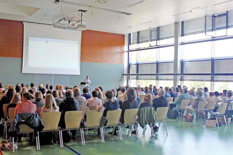 Tantzky Softwareschulung, ca. 100 Menschen sitzen auf Stühlen und schauen zur Bühne,  große Präsentationsleinwand mit TANTZKY Powerpoint Präsentation