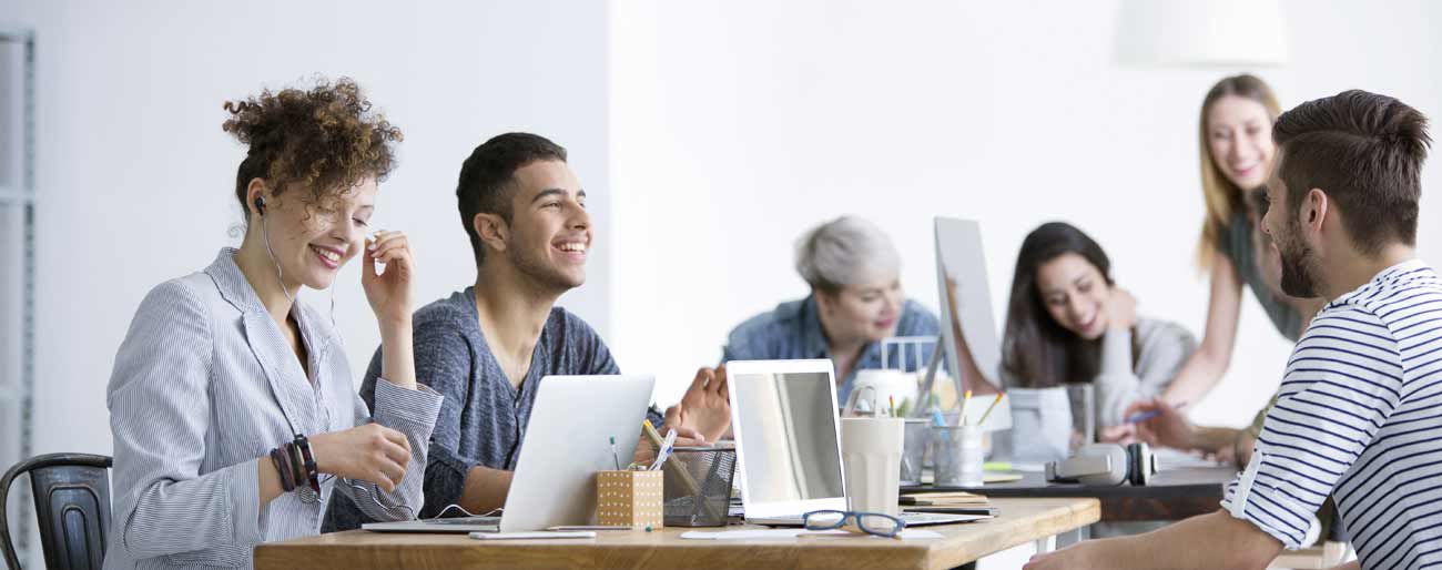 sechs Menschen arbeiten gemeinsam mit Laptops und haben Spaß